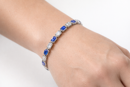Bracelet with blue and clear stones on a wrist against a white background